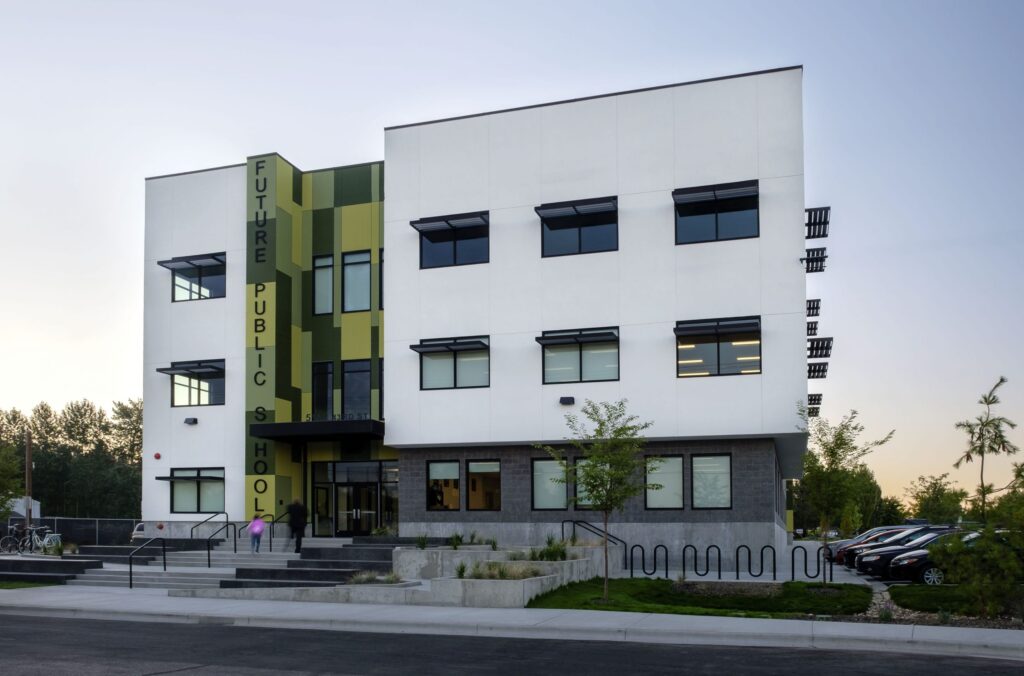 A modern three-story building labeled "Future Public School" with geometric design, surrounded by trees and a parking area, at sunrise.