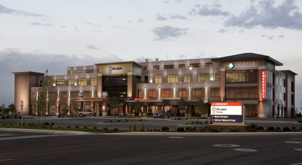 A modern hospital building named St. Luke's in Nampa with clear emergency signage, surrounded by an empty parking lot and evening sky.