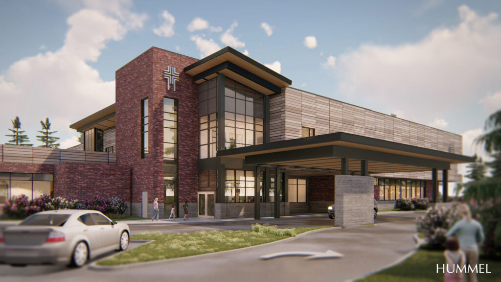 A modern brick building with large windows, featuring a cross symbol. People are near the entrance and a car is parked outside.